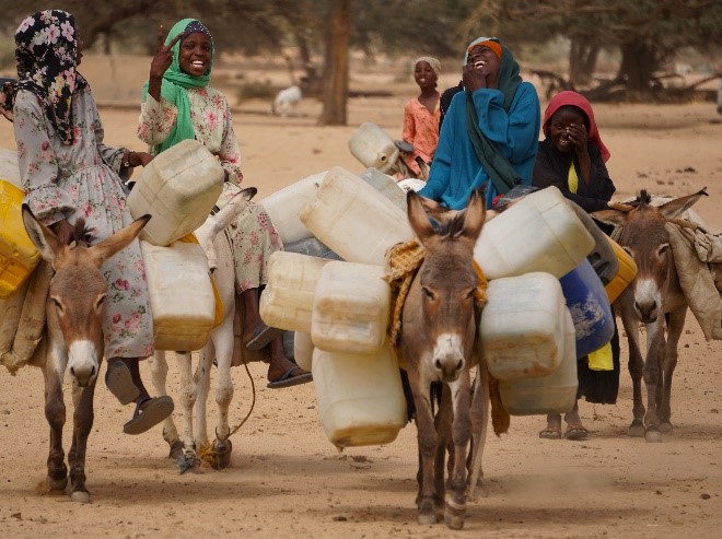 Women hauling water on donkeys.